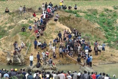 Người dân tập trung xem trục vớt gỗ sưa ở ngầm bến Tróc. (Ảnh: Đức Thọ/Vietnam+)