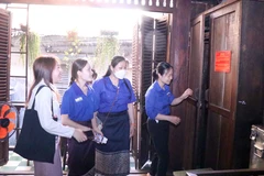 Các lưu học sinh Lào, Campuchia tìm hiểu lối thoát bí mật của lực lượng Biệt động Sài Gòn nằm trong tủ quần áo. (Ảnh: Xuân Khu/TTXVN) 