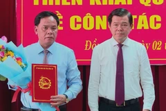 Bí thư Tỉnh ủy Đồng Nai Nguyễn Hồng Lĩnh trao quyết định và tặng hoa chúc mừng ông Võ Tấn Đức được giao làm quyền Chủ tịch UBND tỉnh Đồng Nai. (Ảnh: TTXVN phát) 