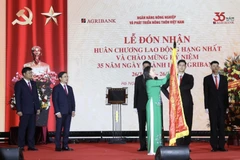 Phó Chủ tịch nước Võ Thị Ánh Xuân gắn Huân chương Lao động hạng Nhất lên lá cờ truyền thống của Ngân hàng Nông nghiệp và Phát triển nông thôn. (Ảnh: Lâm Khánh/TTXVN)