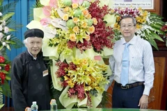 Phó Bí thư Thường trực Tỉnh ủy, Chủ tịch Hội đồng Nhân dân tỉnh An Giang Lê Văn Nưng (phải) tặng hoa chúc mứng Ban Trị sự Trung ương Giáo hội Phật giáo Hòa Hảo nhân kỷ niệm 84 năm Ngày Đức Huỳnh Giáo chủ khai sáng đạo Phật giáo Hòa Hảo. (Ảnh: Công Mạo/TTX