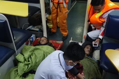 Hai bệnh nhân được hỗ trợ y tế trên tàu SAR 412 trước khi chuyển về bờ. (Ảnh: TTXVN phát)