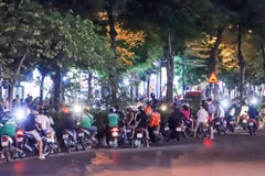Hàng trăm thanh thiếu niên tràn ra lòng đường hóng chốt 141 làm nhiệm vụ tại phố Xã Đàn, Đống Đa. (Ảnh: Phạm Kiên/TTXVN) 