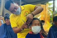 Anh Ngô Trọng Giáp cắt tỉa, căn chỉnh cẩn thận từng mái tóc cho bệnh nhân đang điều trị tại Bệnh viện Đa khoa huyện Triệu Phong. (Ảnh: TTXVN phát)