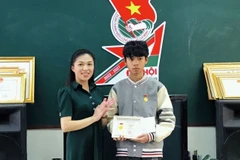 Chị Trần Diệp Mỹ Dung, Phó Bí thư Tỉnh Đoàn, Chủ tịch Hội đồng Đội tỉnh Lâm Đồng thừa ủy quyền của Trung ương Đoàn trao tặng Huy hiệu Tuổi trẻ dũng cảm cho em Nguyễn Trung Hiếu. (Ảnh: TTXVN phát)