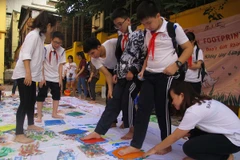 In dấu chân lên tấm vải trắng, một hoạt động để truyền tải thông điệp 'không sử dụng, không chấp nhận và không dùng sừng tê giác làm quà tặng.' (Ảnh: Tiến Đạt/Vietnam+)