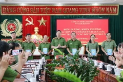 Đại tá Phạm Hải Đăng, Phó Giám đốc Công an tỉnh Lai Châu thưởng nóng cho các đơn vị nghiệp vụ phá án tại Lễ biểu dương. (Ảnh: Nguyễn Oanh/TTXVN)