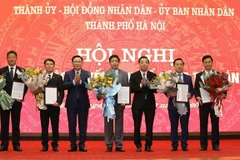Bí thư Thành ủy Vương Đình Huệ và Chủ tịch UBND thành phố Chu Ngọc Anh trao quyết định và tặng hoa chúc mừng năm tân Phó Chủ tịch UBND thành phố Hà Nội. (Ảnh: Văn Điệp/TTXVN)