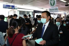 Phó Thủ tướng kiêm Bộ trưởng Y tế Thái Lan Anutin Charnvirakul (phải) phát khẩu trang cho hành khách tại một nhà ga ở Bangkok hồi tháng 2/2020. (Ảnh: AFP/TTXVN)