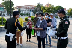 Lực lượng quân cảnh Campuchia phát khẩu trang miễn phí cho người dân tại Phnom Penh. (Ảnh: AFP/TTXVN)
