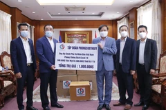 Chủ tịch Tập đoàn Phongsubthavy của Lào, ông Phongsavath Senaphuan (trái) đang trao tượng trưng tấm biển số tiền và vật tư y tế trị giá 1 triệu USD cho Đại sứ Nguyễn Bá Hùng để ủng hộ Quỹ phòng chống COVID-19 của Việt Nam. (Ảnh: Phạm Kiên/TTXVN)