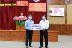 Đại diện Đài Phát thanh-Truyền hình Vĩnh Long trao bảng ủng hộ 3 tỷ đồng. (Ảnh: Phạm Minh Tuấn/TTXVN)