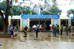 Lực Công an huyện Hưng Nguyên (Nghệ An) cùng giáo viên Trường Tiểu học Phạm Hồng Thái (xã Châu Nhân, huyện Hưng Nguyên) dọn vệ sinh môi trường sau mưa lũ để học sinh sớm đi học trở lại. (Ảnh: Tá Chuyên/TTXVN)