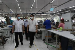Đoàn công tác kiểm tra công tác phòng, chống COVID-19 tại Công ty TNHH May Nhà Bè. (Ảnh: Hồng Thái/TTXVN)
