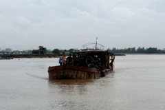 Lai dắt chiếc tàu khai thác cát trái phép vào bờ để xử lý. (Ảnh: Mạnh Tú/TTXVN)