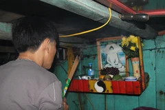 Ngư dân thực hiện nghi thức "cúng thuyền" cuối năm trong khoang lái của phương tiện. (Ảnh: Xuân Tiến/TTXVN)
