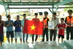 Đoàn viên, thanh niên Bộ đội Biên phòng Kiên Giang tặng cờ Tổ quốc, ảnh Bác cho ngư dân. (Ảnh: TTXVN phát)