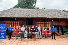 Nhóm các bạn trẻ Khanh Son Eco cùng đoàn khách du lịch chụp ảnh lưu niệm tại nhà dài của người đồng bào dân tộc Raglai, nhằm giới thiệu một sản phẩm văn hóa của huyện Khánh Sơn. (Ảnh: TTXVN phát)