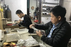 Nghệ nhân Phạm Bình Minh kiểm tra chất lượng dây truyền bạc. (Ảnh: Tiến Vĩnh/TTXVN)