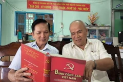 Ông Lê Văn Thiệm (bên trái) tại ấp 6, thị trấn Giồng Trôm (Bến Tre), Đảng viên 35 năm tuổi đảng trao đổi nghiên cứu văn kiện của Đảng với đảng viên trong chi bộ. (Ảnh: Huỳnh Phúc Hậu/TTXVN)