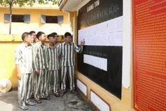 Phạm nhân tại Trại giam Ninh Khánh xem danh sách phạm nhân đủ điều kiện đề nghị đặc xá năm 2024 được niêm yết công khai tại bảng tin. (Ảnh: Hải Yến/TTXVN)