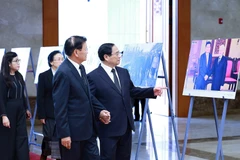 Thủ tướng Phạm Minh Chính giới thiệu với Tổng Bí thư, Chủ tịch nước Lào Thongloun Sisoulith một số hình ảnh về hoạt động đối ngoại của Tổng Bí thư Nguyễn Phú Trọng. (Ảnh: Dương Giang/TTXVN)