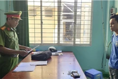 Điều tra viên tống đạt quyết định bắt tạm giam đối với Lâm Văn Sel. (Ảnh: TTXVN phát)