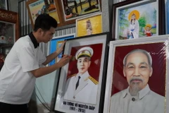 Anh Nguyễn Minh Trí hoàn thiện bức tranh gói vải chân dung Đại tướng Võ Nguyên Giáp. (Ảnh: Văn Sĩ/TTXVN)