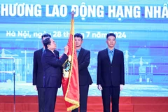 Chủ tịch Quốc hội Trần Thanh Mẫn gắn Huân chương Lao động hạng Nhất lên cờ truyền thống của Tổng Liên đoàn Lao động Việt Nam. (Ảnh: Minh Đức/TTXVN)