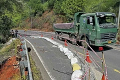 Cơ quan chức năng đã triển khai các biện pháp đảm bảo an toàn giao thông tại khu vực bị sạt lở và bố trí nhân sự trực điều tiết giao thông trên đèo Tà Nung. (Ảnh: Nguyễn Dũng/TTXVN)