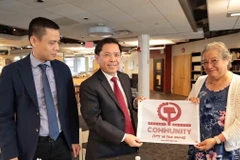 Bà Rossana Cambron, đồng Chủ tịch Đảng Cộng sản Mỹ (phải), tặng đồng chí Nguyễn Văn Thể, Ủy viên Trung ương Đảng, Bí thư Đảng ủy Khối các Cơ quan Trung ương cờ của Đảng Cộng sản Mỹ. (Ảnh: Thanh Tuấn/TTXVN)