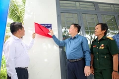Trưởng Ban Tuyên giáo Trung ương Nguyễn Trọng Nghĩa (giữa) và ông Vũ Mạnh Hùng, Chủ tịch HĐQT - Tổng giám đốc Tập đoàn Hùng Nhơn thực hiện nghi thức mở bảng nhà, trao nhà tình nghĩa cho cựu chiến binh Dương Thị Thu Sương. (Ảnh: Giang Phương/TTXVN)