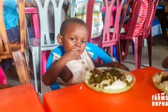Một em bé mồ côi thưởng thức bữa ăn với ấu trùng mọt cọ. (Nguồn: Farms for Orphans)