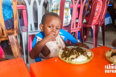 Một em bé mồ côi thưởng thức bữa ăn với ấu trùng mọt cọ. (Nguồn: Farms for Orphans)