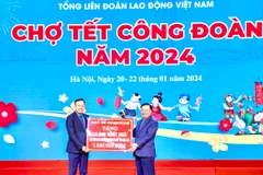 Ông Đinh Tiến Dũng, Ủy viên Bộ Chính trị, Bí thư Thành ủy Hà Nội trao biển tượng trưng kinh phí tặng quà Tết cho đoàn viên, người lao động. (Ảnh: Minh Nghĩa/TTXVN)