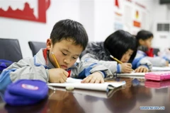 Học sinh tiểu học làm bài tập về nhà tại một trung tâm chăm sóc sau giờ học ở quận tự trị Yuping Dong, tỉnh Quý Châu, Tây Nam Trung Quốc. (Ảnh: Tân Hoa xã)