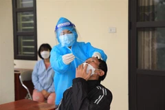 Nhân viên y tế Trạm y tế lưu động số 1 xã Tân Triều, huyện Thanh Trì lấy mẫu xét nghiệm sàng lọc cho người dân trước khi hết cách ly, điều trị. (Ảnh: Hoàng Hiếu/TTXVN)