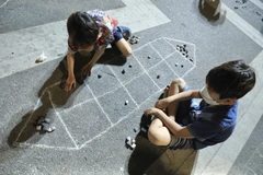 Trẻ em tìm hiểu, chơi trò dân gian “ô ăn quan”. (Ảnh: Hoàng Hiếu/TTXVN)