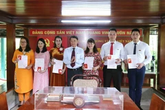 Ông Nguyễn Đức Lợi, Ủy viên Trung ương Đảng, Bí thư Đảng ủy, Tổng Giám đốc TTXVN trao thẻ Đảng viên đợt 19-5 tại Nhà sàn Bác Hồ. (Ảnh: Phương Hoa/TTXVN)