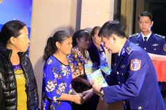 Thượng tá Lê Huy, Phó Chính ủy Bộ Tư lệnh vùng Cảnh sát biển 1, trao quà cho các gia đình chính sách trên huyện đảo Bạch Long Vĩ. (Ảnh: An Đăng/TTXVN)