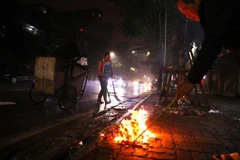 Người dân đốt vàng mã ngay trên vỉa hè làm lượng rác tăng cao khiến nhân viên vệ sinh môi trường phải quét thường xuyên để đảm bảo các tuyến phố sạch vào sáng đầu tiên của năm mới. (Ảnh: Lâm Khánh/TTXVN)