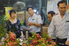 Cán bộ Ban Quản lý an toàn thực phẩm Thành phố Hồ Chí Minh kiểm tra trái cây, hóa đơn mua bán tại Chợ nông sản Thủ Đức. (Ảnh: Đinh Hằng/TTXVN)