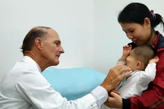 Bác sỹ McKay McKinnon khám lâm sàng cho một trẻ em bị dị dạng hốc mắt. (Ảnh: TTXVN phát)