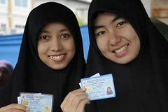 Phụ nữ người Hồi giáo Thái Lan giới thiệu thẻ căn cước của họ trước khi bỏ phiếu. (Nguồn: AFP/TTXVN)