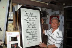 Nghệ nhân Lê Văn Kinh và bức tranh thêu Cáo tật thị chúng. (Ảnh: Quốc Việt/Vietnam+)