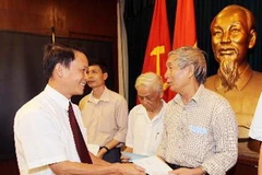 Tổng giám đốc Thông Tấn Xã Việt Nam Nguyễn Đức Lợi trao sổ tiết kiệm cho thân nhân liệt sỹ tại Lễ kỷ niệm. (Ảnh: Quốc Khánh/TTXVN)