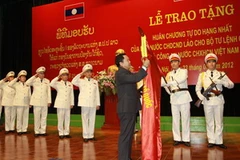 Gắn Huân chương Tự do Hạng nhất của Nhà nước Lào lên lá cờ truyền thống của Bộ Tư lệnh Cảnh vệ. (Ảnh: Doãn Tấn/Vietnam+)