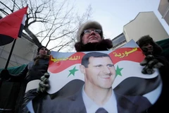 Người dân Nga mang theo chân dung Tổng thống al-Assad, bày tỏ sự ủng hộ đối với chính quyền Syria. (Nguồn: AFP/TTXVN)
