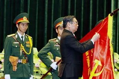 Thường trực Ban Bí thư Lê Hồng Anh gắn danh hiệu Anh hùng lực lượng vũ trang nhân dân lên lá cờ truyền thống của Văn phòng TW Cục miền Nam. (Ảnh: Thế Anh/TTXVN)