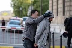 Cảnh sát áp giải kẻ tình nghi sau khi bị bắt giữ. (Nguồn: AFP/TTXVN)